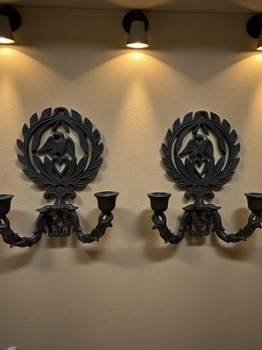 A pair of vintage cast iron wall sconces with eagle and laurel wreath motif